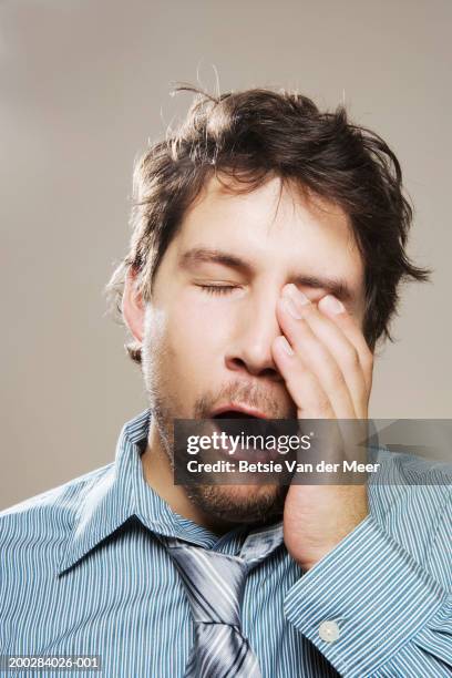 man wearing shirt and loosened tie yawning, rubbing eye, close-up - gähnen stock-fotos und bilder