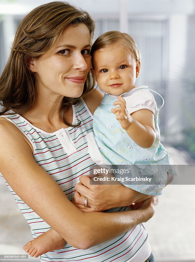Mother holding baby daughter (6-9 months), smiling, portrait