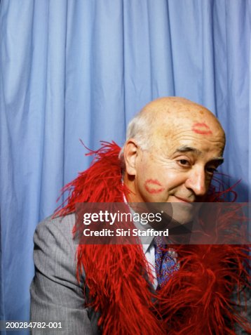 Senior man with kiss marks on face and head in phone booth Senior man with kiss marks on face and head in phone booth
