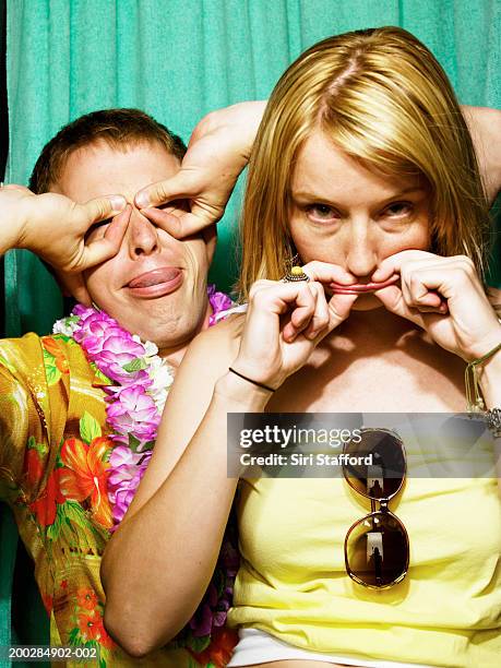 young couple making faces in photo booth - photo booth stockfoto's en -beelden