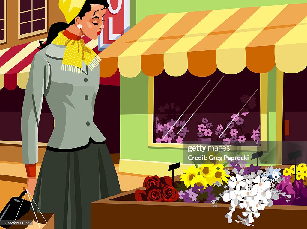 Woman looking at plants in box outside flower shop, side view