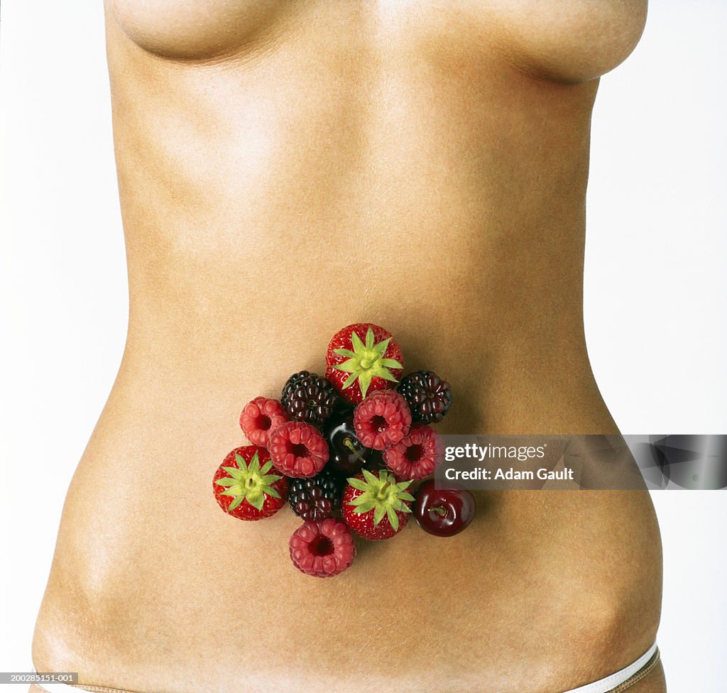 Woman with fruit over abdomen, mid section