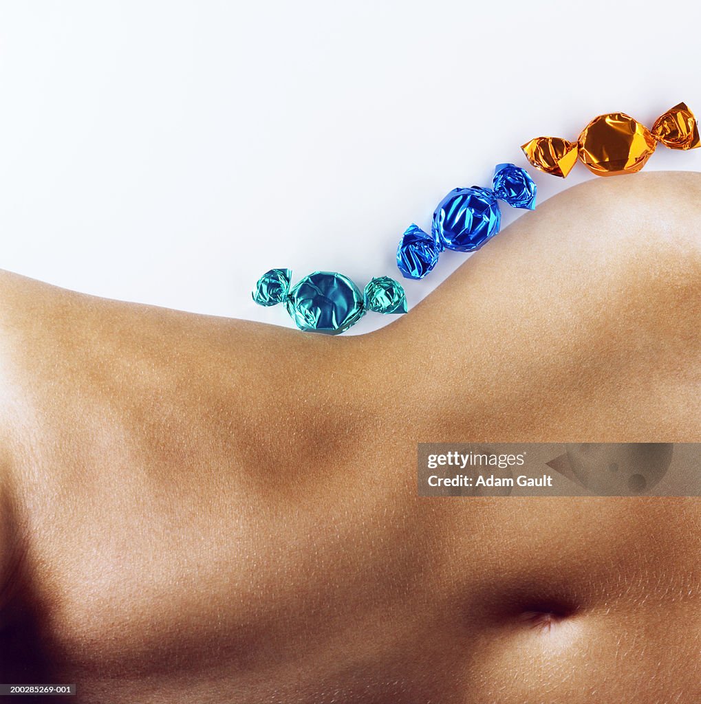 Woman with sweets in line 'along hip', mid section