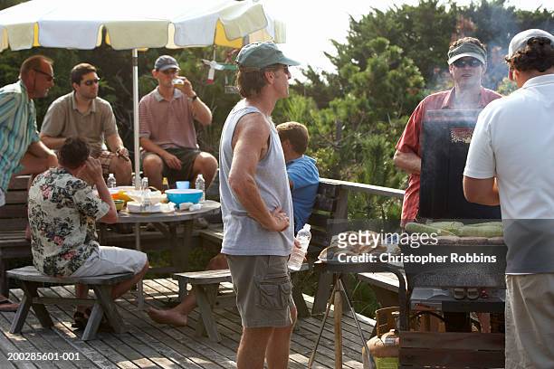 group of men having barbecue on decking - white shorts stock pictures, royalty-free photos & images