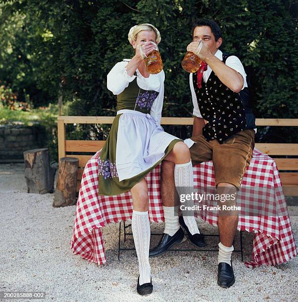 couple sitting on table drinking beer steins outdoors - biergarten münchen foto e immagini stock