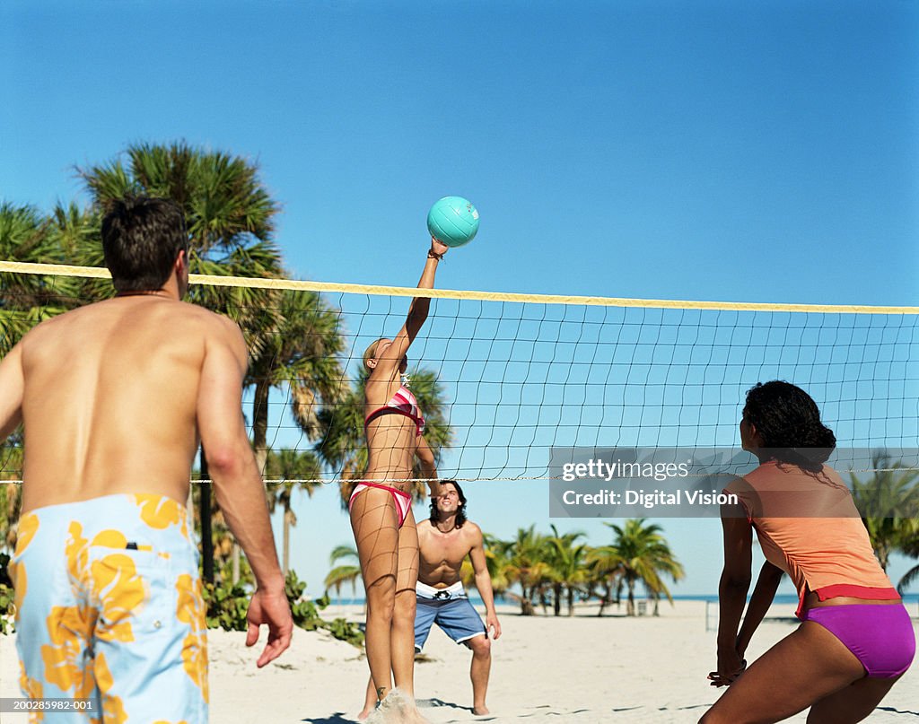 Four people playing volleyball on beach