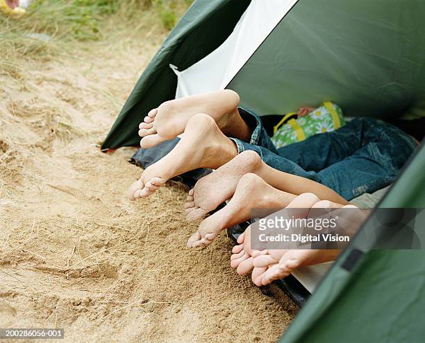 friends lying in tent, feet poking out entrance, low section, close-up - woman lying on stomach with feet up foto e immagini stock