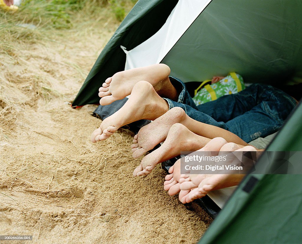 Friends lying in tent, feet poking out entrance, low section, close-up