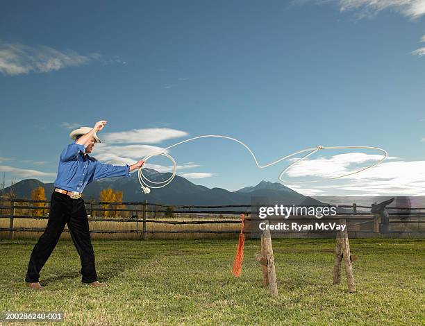 young man lassoing sawhorse with cattle head on front, side view - laço corda - fotografias e filmes do acervo