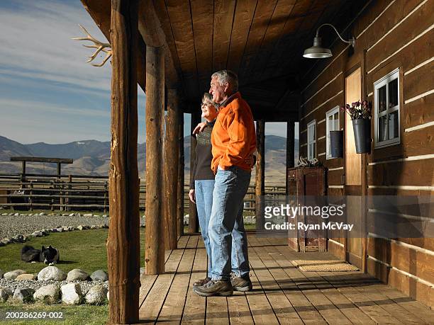 senior man and woman standing on porch, embracing, side view - montana ranch stock pictures, royalty-free photos & images