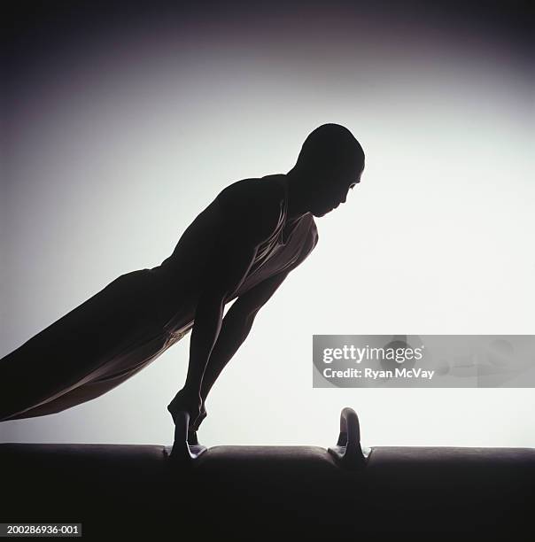 male gymnast performing on pommel horse, silhouette - voltigeerpaard stockfoto's en -beelden