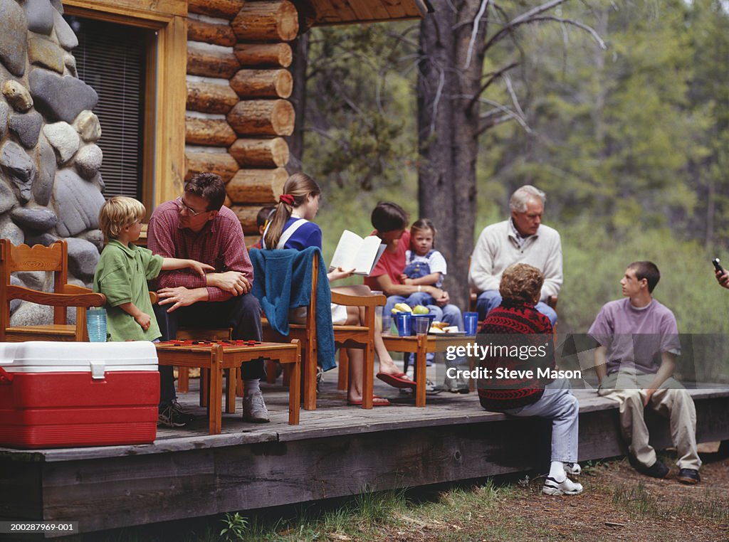 Family sitting on wooden porch of mountain lodge