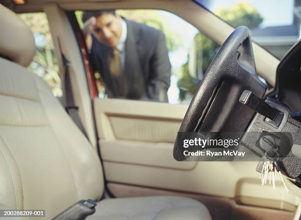 businessman looking through window at keys locked in car - lock fotografías e imágenes de stock