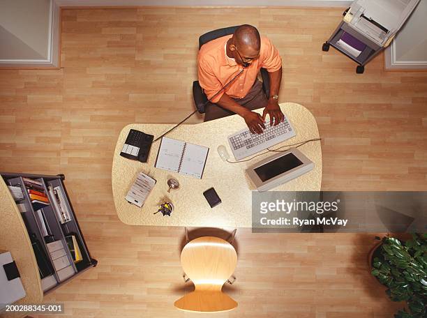 man working on computer in office, talking on phone overhead view - festnetztelefon stock-fotos und bilder