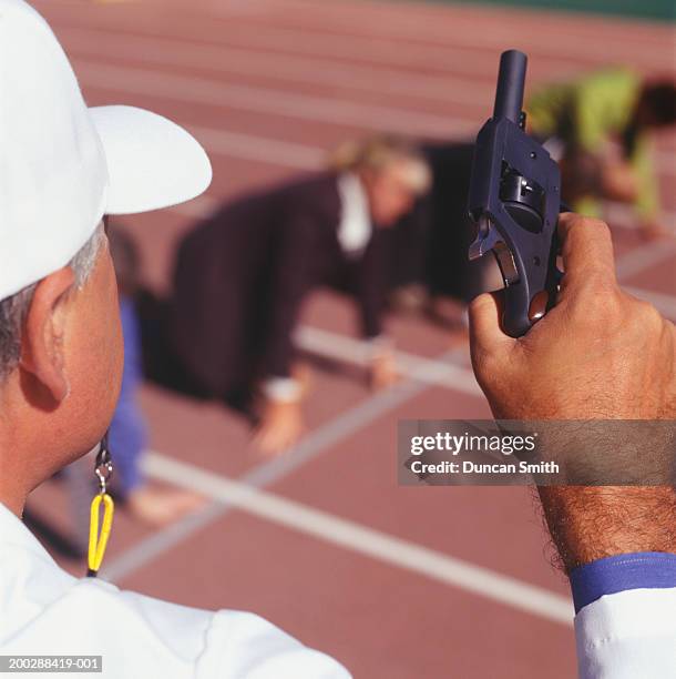 coach holding starting gun in stadium, elevated view - startschot stockfoto's en -beelden