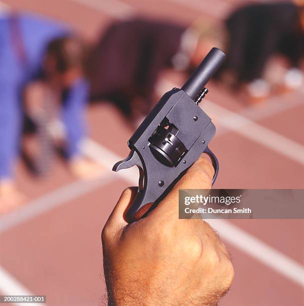 coach holding starting gun in stadium, close-up of hand - startschot stockfoto's en -beelden