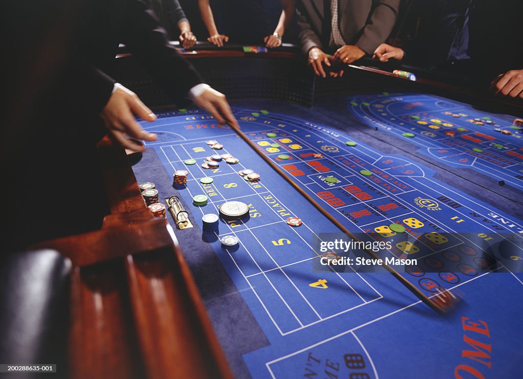 People playing craps in casino, croupier collecting chips