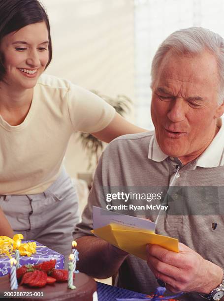 mature man reading birthday wishes in living room - birthday card stock pictures, royalty-free photos & images