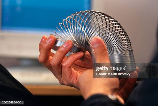 man playing with slinky, close-up of hands - metal coil toy 個照片及圖片檔