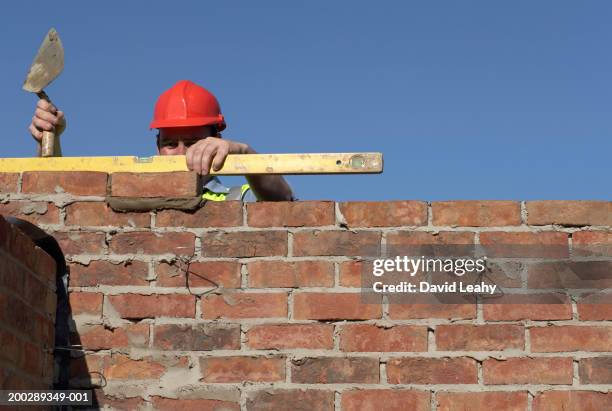 bricklayer checking wall with spirit level - brick layer stock-fotos und bilder