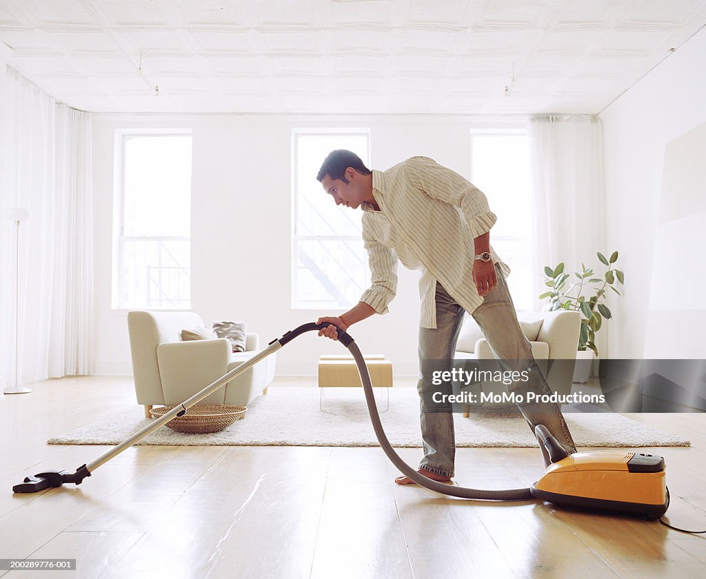 Man vacuuming living room floor, side view