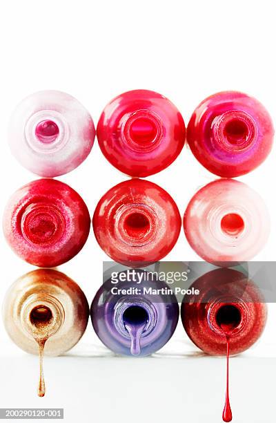 nail varnish dripping from bottles stacked on their sides, close-up - gold nail polish stock-fotos und bilder