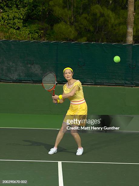 mature woman preparing to return tennis ball - atuendo de tenis fotografías e imágenes de stock