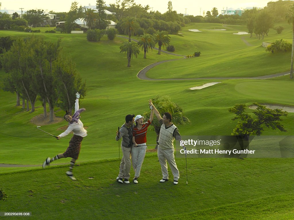 Young and mature couples celebrating on golf course (blurred motion)