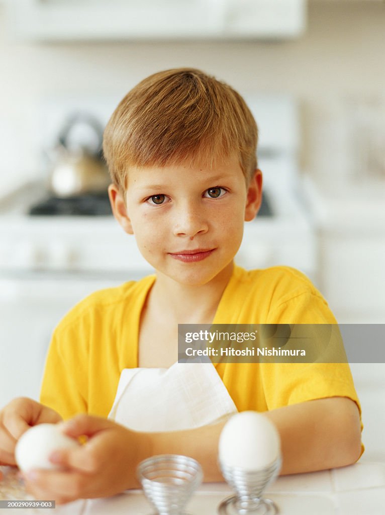 Boy (6-7) holding hard boiled egg, portrait