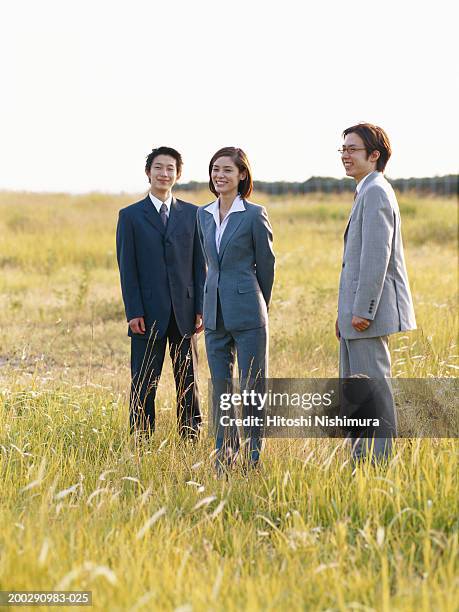 business people standing in field, smiling - bussines group suit tie stock-fotos und bilder