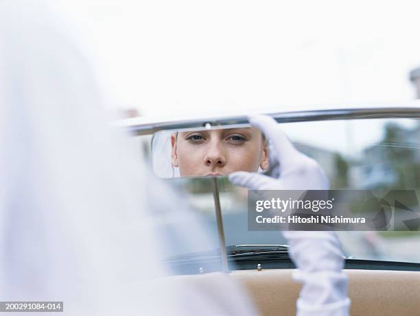 bride in convertible car, looking into rear view mirror - car mirror stock-fotos und bilder