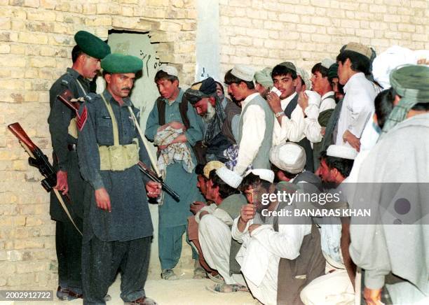 Pakistani paramilitary troops stand guard 10 October 2002 as people wait in a queue to cast their votes in the general election in country's southern...