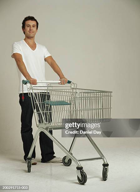 man holding shopping trolley, smiling, portrait - man pushing stock pictures, royalty-free photos & images