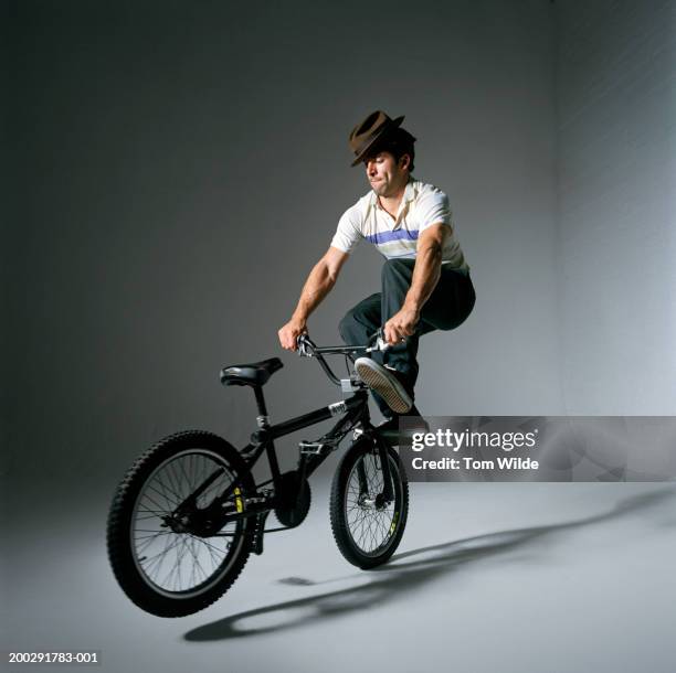 man wearing hat balancing on front of bicycle - bmx stock-fotos und bilder