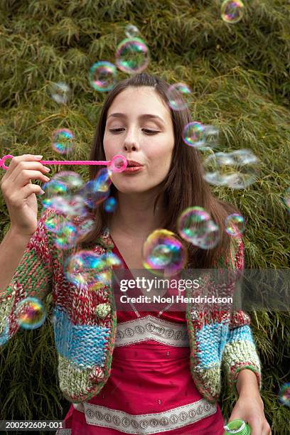 teenage girl (13-15 years) blowing soap bubbles through bubble wand outdoors - 14 15 years girl stock pictures, royalty-free photos & images