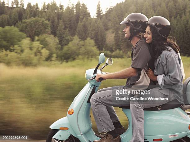 man and young woman riding on motor scooter, side view - motorized vehicle riding foto e immagini stock