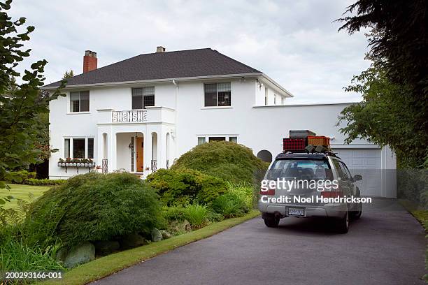 sports utility vehicle parked in front drive of house, loaded with luggage - car in driveway foto e immagini stock