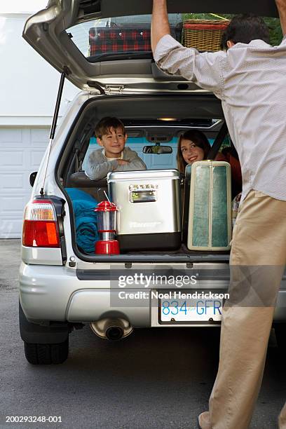 boy and girl (8-13 years) in back seat of car, smiling at father, rear view, closing boot lid - closing car boot fotografías e imágenes de stock