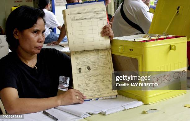 Poll clerk shows the records and thumbprint of Joseph Estrada where he is a registered voter at the polling center in Pedro Cruz school, where the...