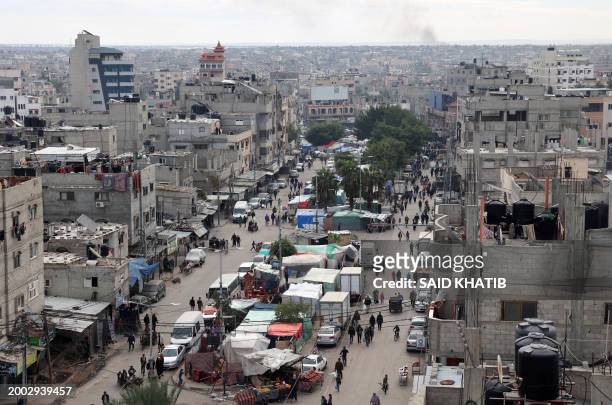 People walk past tents set up for displaced Palestinians in the heart of Rafah in the southern Gaza Strip on February 14 amid the continuing battles...