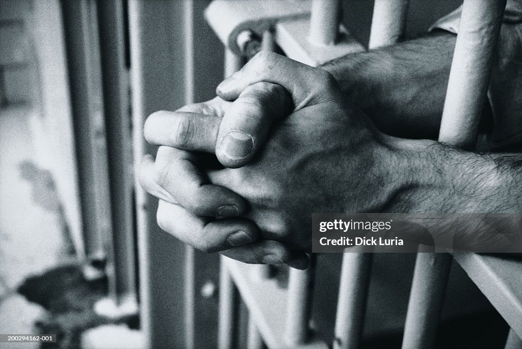 Hands on prison bars