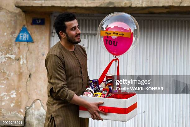 An Afghan man carrying a birthday gift hamper walks along a street in Kabul on February 14, 2024.