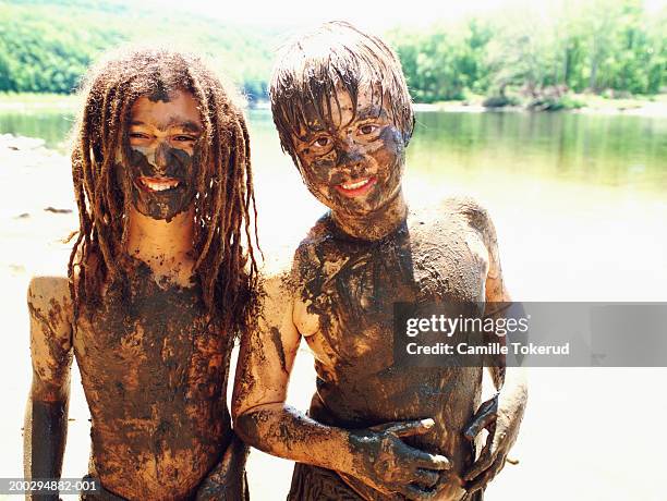 two boys (8-12) covered in mud, portrait, lake in background - people covered in mud stock pictures, royalty-free photos & images