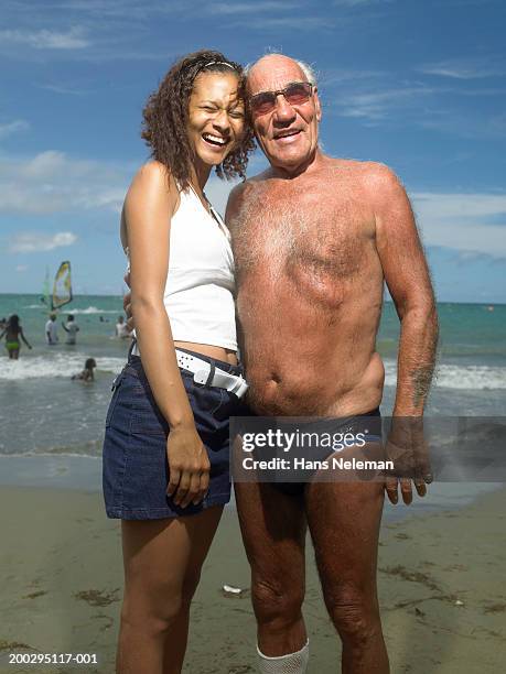 senior man and young woman on beach, portrait - hispanic man on beach stock-fotos und bilder