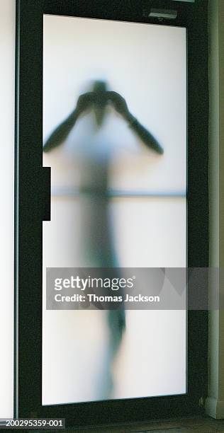 silhouette of man looking through frosted glass door (backlit) - vouyer stock pictures, royalty-free photos & images