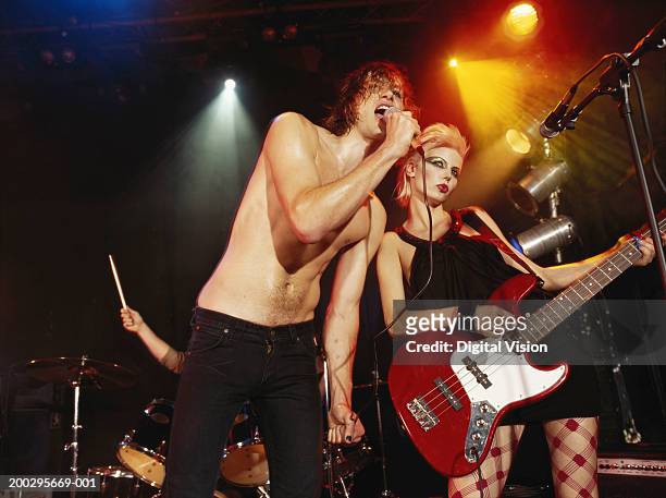 man singing into microphone by woman playing bass guitar - bas nylon stockfoto's en -beelden