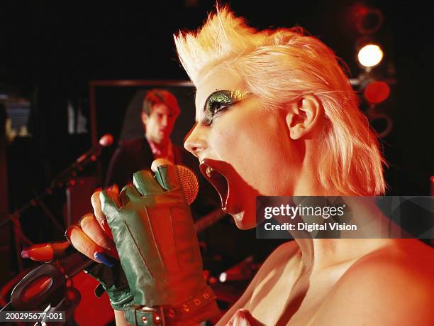 woman singing into microphone, side view - boygroup stock-fotos und bilder