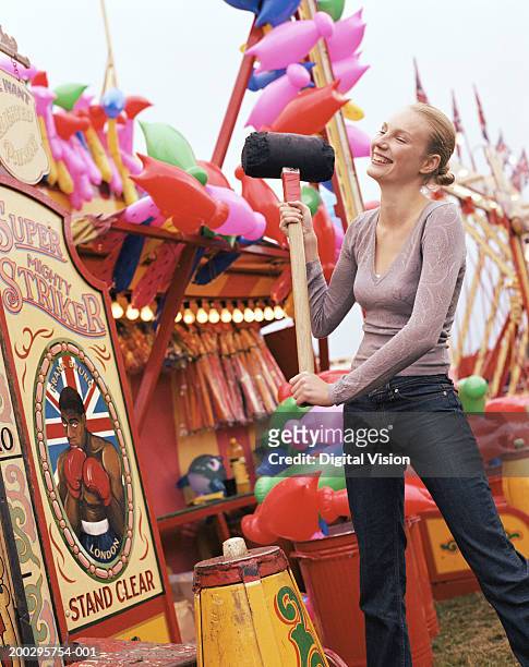 young woman testing strength at fairground, smiling - strength tester stock pictures, royalty-free photos & images