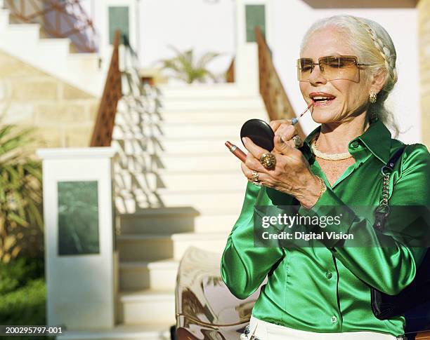 mature woman standing by car, applying make-up - glamour ストックフォトと画像