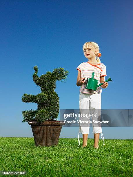girl (5-7) holding water can, topiary on side - topiary stock pictures, royalty-free photos & images